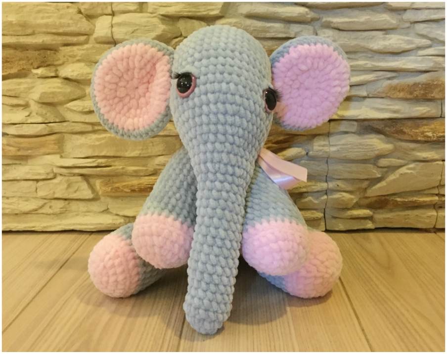 a crocheted elephant sitting on a wooden floor.