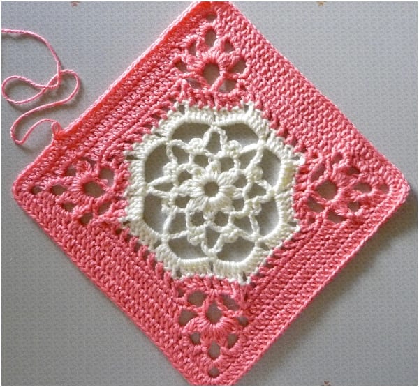 A lacy pink and white crochet square.
