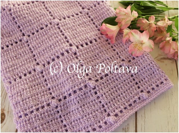 a purple crocheted baby blanket with flowers on it.