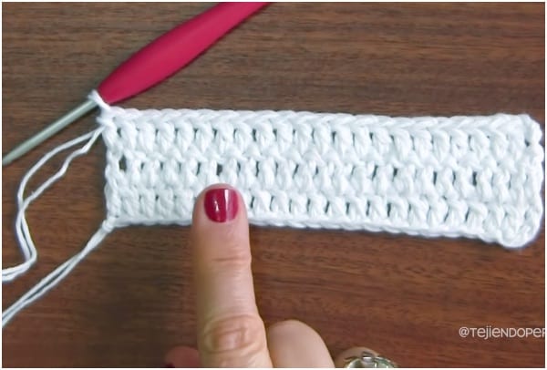 a person is holding a crochet needle and a crochet hook.