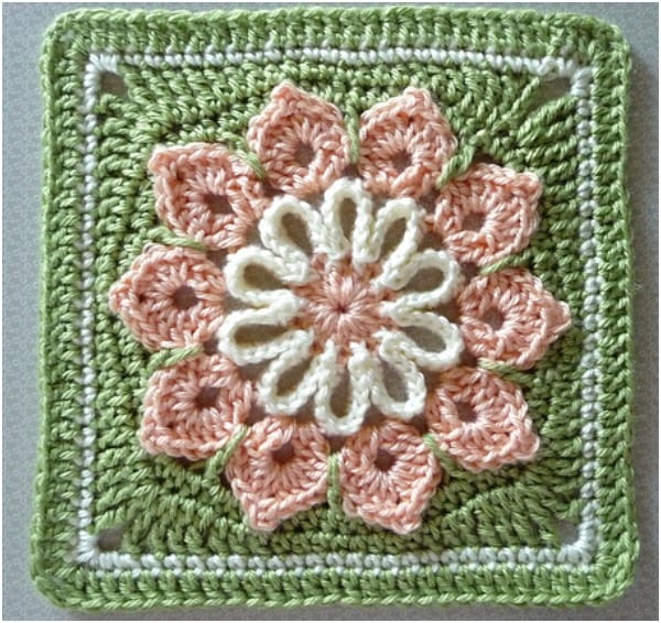 a crocheted square with a flower on it.