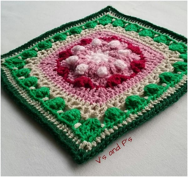 a crocheted square with pink and green flowers.