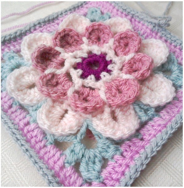 a crocheted square with a flower on it.