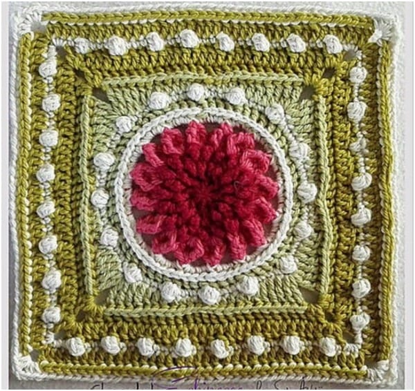 a crocheted square with a flower on it.