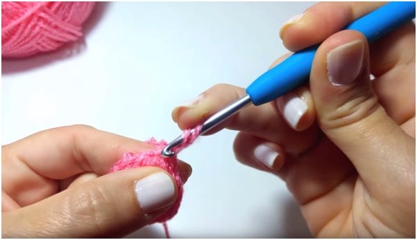 a person is holding a pink crochet hook.