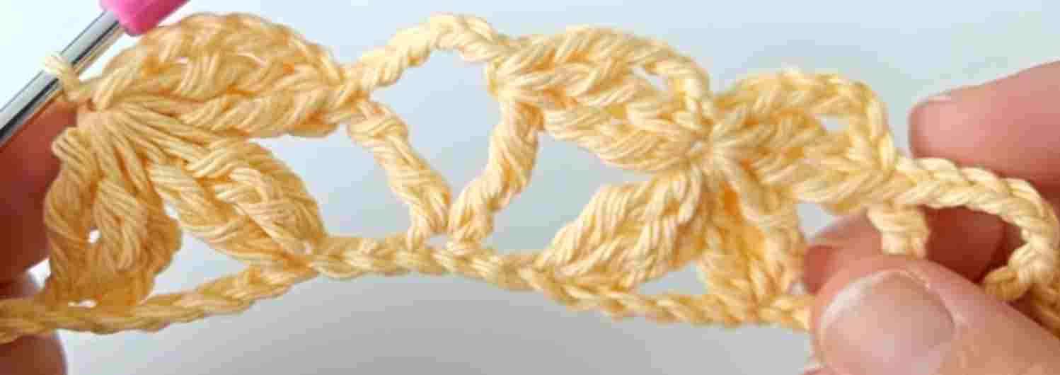 A person is crocheting with a yellow crochet hook.