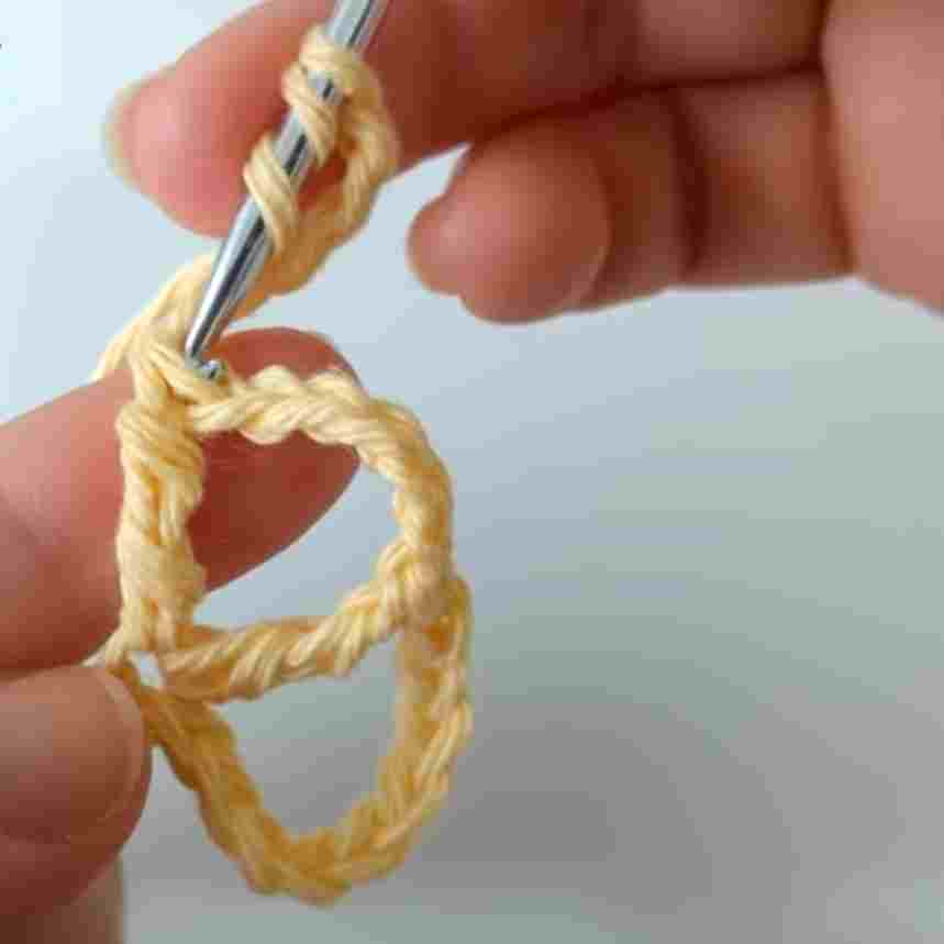 A person is holding a crochet hook to make a crochet stitch.