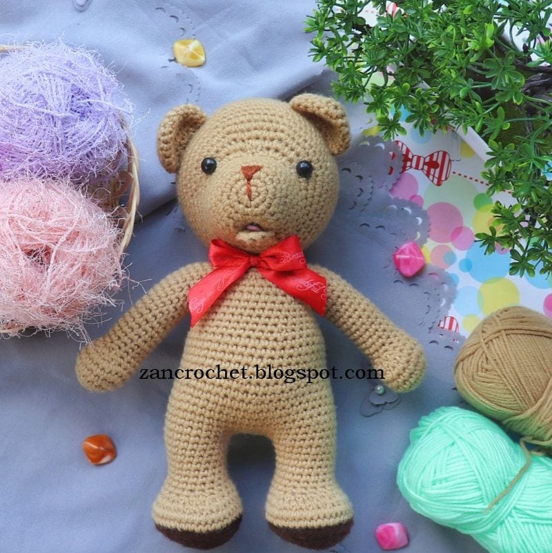 a photo with sweet bear amigurumi with open mouth among skeins of yarn