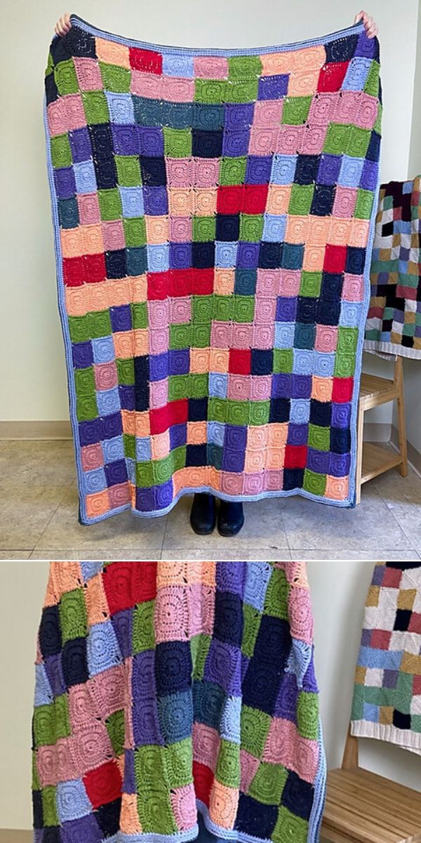 A woman is holding up a colorful crochet blanket.