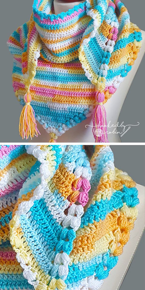 A colorful, crocheted triangular shawl featuring pastel stripes of yellow, pink, blue, and white with tassels on the corners. 