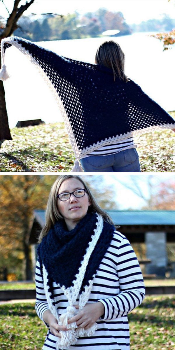 Woman outdoors wearing a large crocheted navy blue and white triangle crochet shawl with tassels.