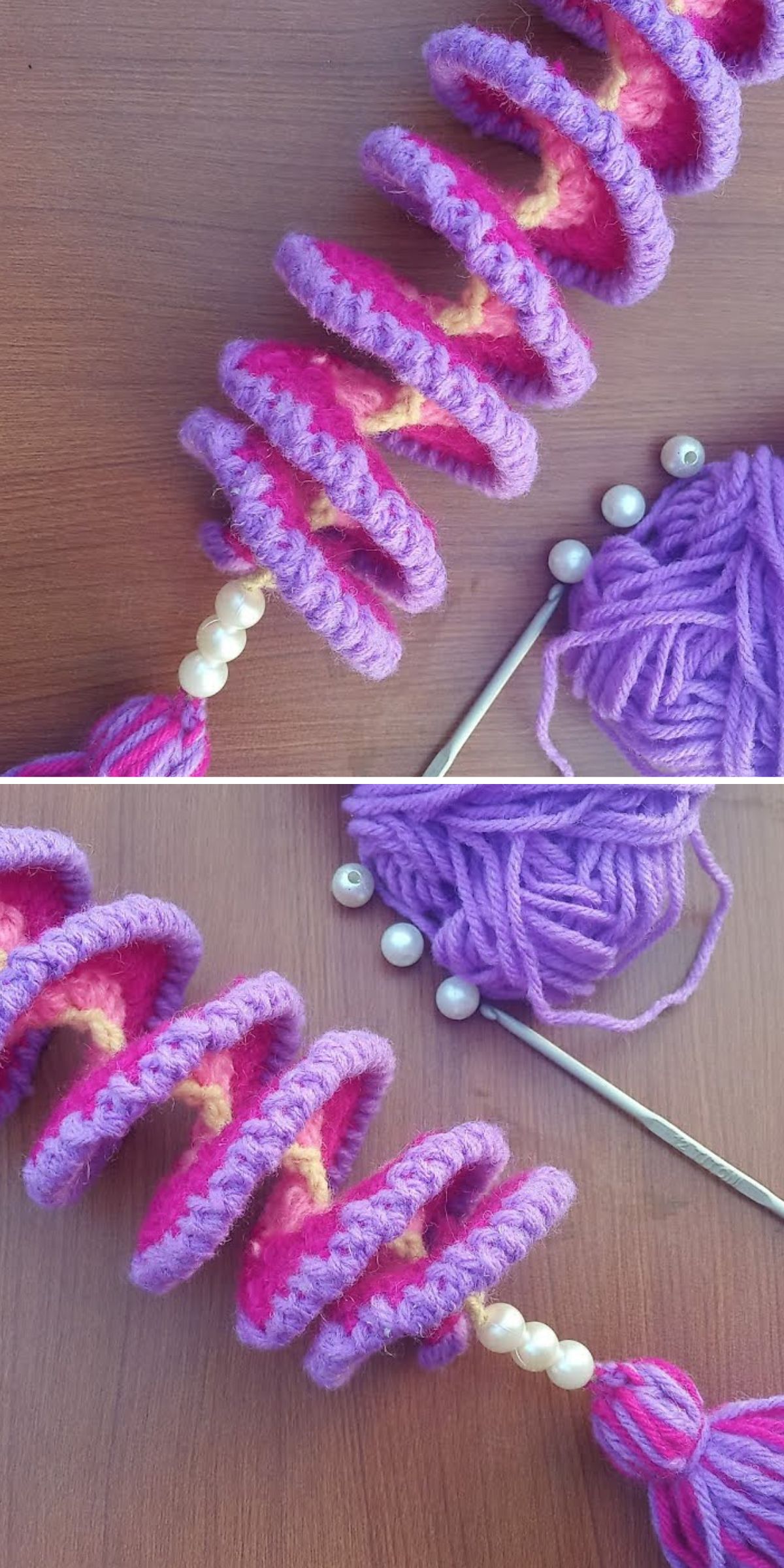 Close-up of a spiral crocheted object with alternating pink and purple yarn, adorned with pearls, resembling crochet windspinners. It lies gracefully on a wooden surface beside knitting needles and yarn.