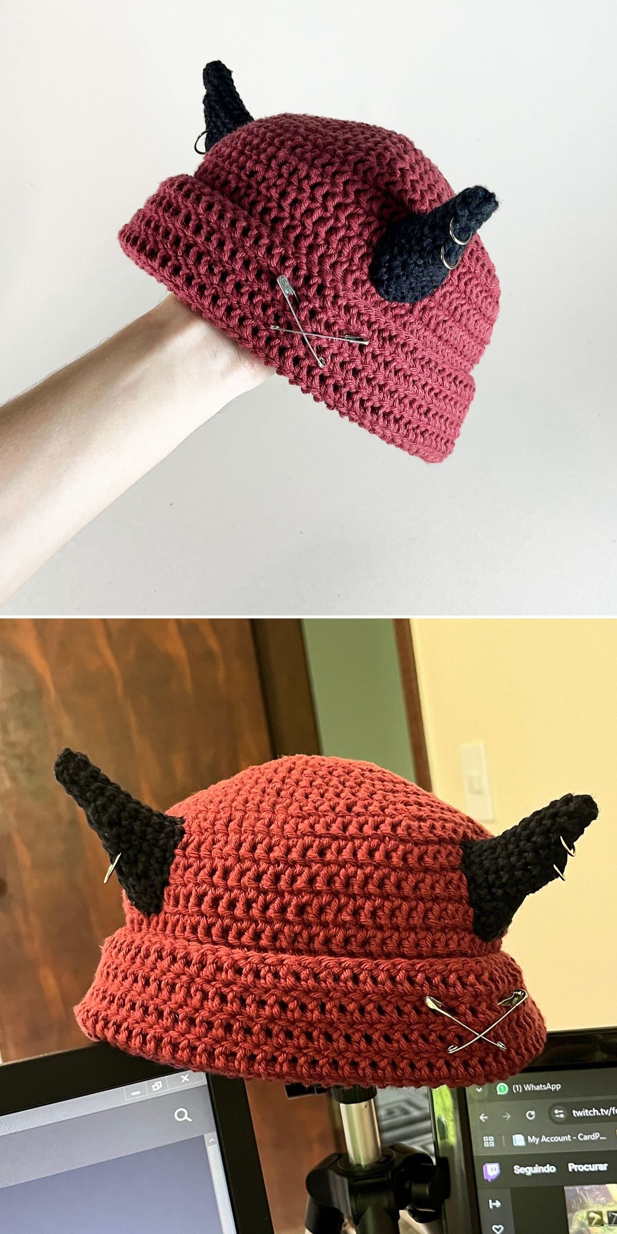 A red crocheted hat with two black horn-like protrusions and several safety pins attached, shown from two different angles.