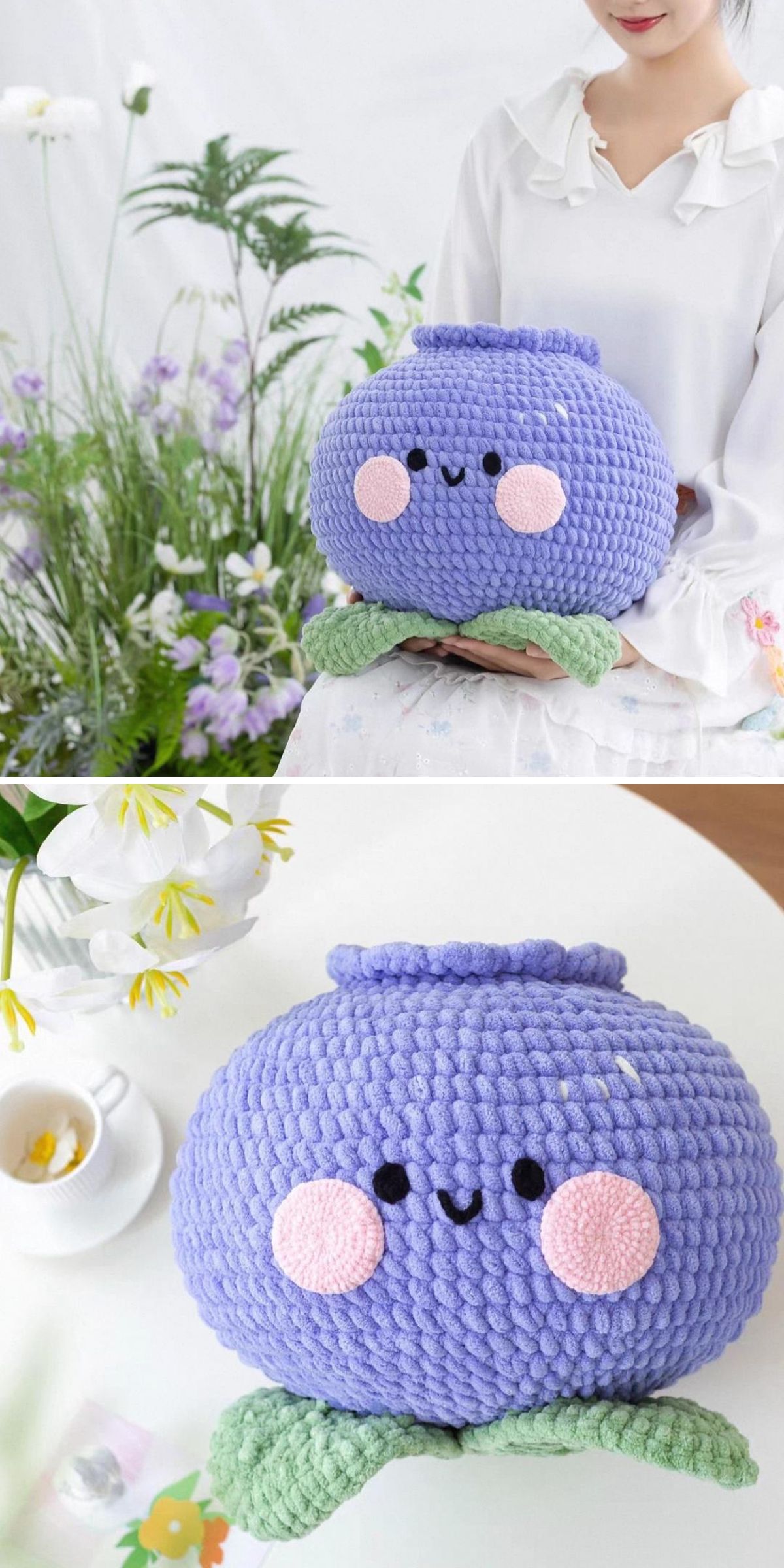 A person holds a round, purple, crocheted plush pillow with a smiling face, pink cheeks, and green leaf-like feet. The blueberry pillow is also shown resting on a table.