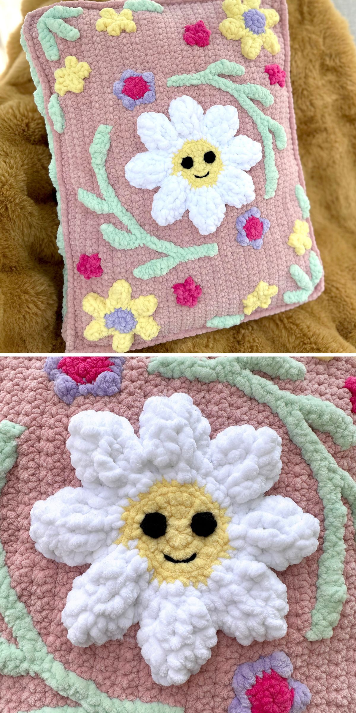 A square pink crochet pillow with a raised white daisy design featuring a smiling face, surrounded by green vines and yellow and pink flowers. Close-up shows the daisy texture in detail.