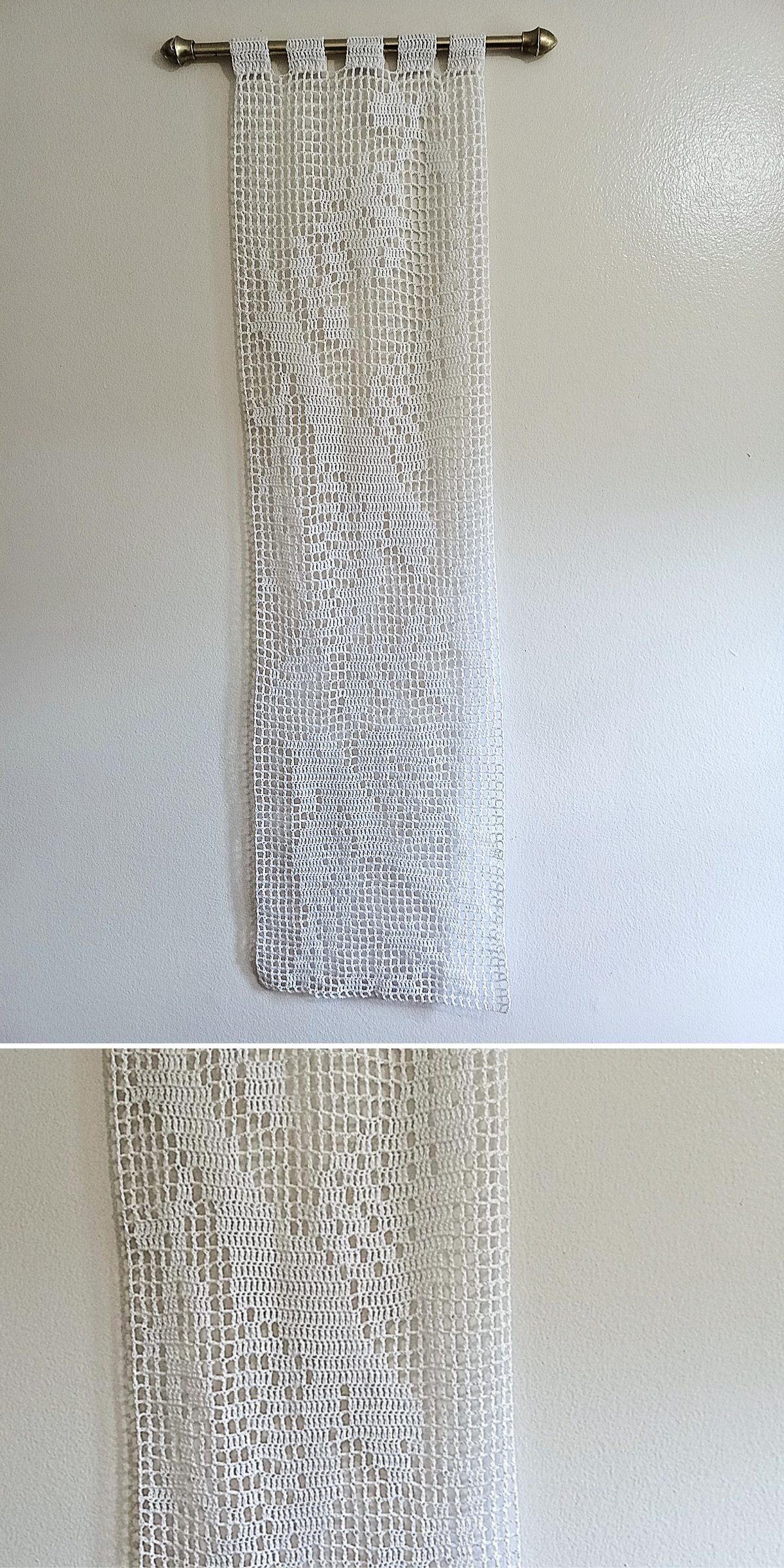 A white crocheted curtain with a floral pattern, perfect for crochet home decor, is displayed on a metal rod against a plain white wall.
