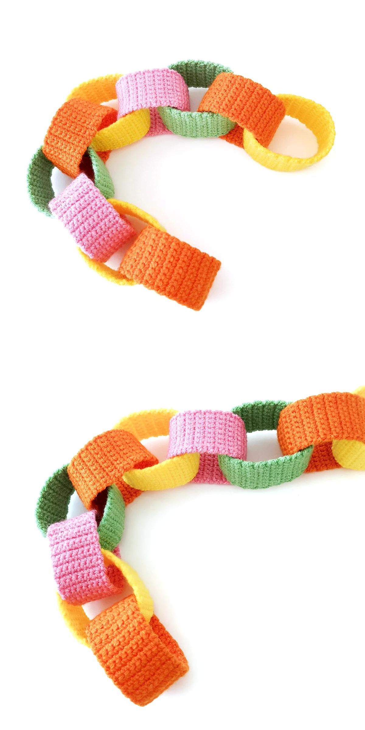 A colorful chain made of crocheted links in orange, pink, yellow, and green, arranged on a white background—the perfect touch for playful crochet home decor.