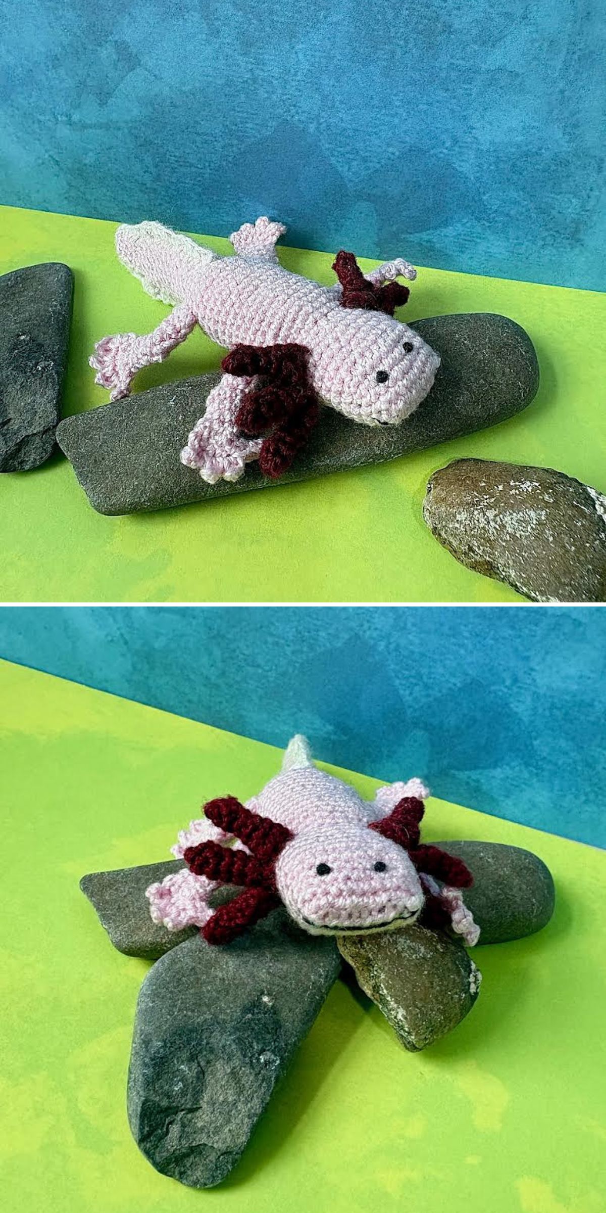 Two crochet axolotl toys in pink and burgundy yarn are positioned on gray rocks against a blue and green background.