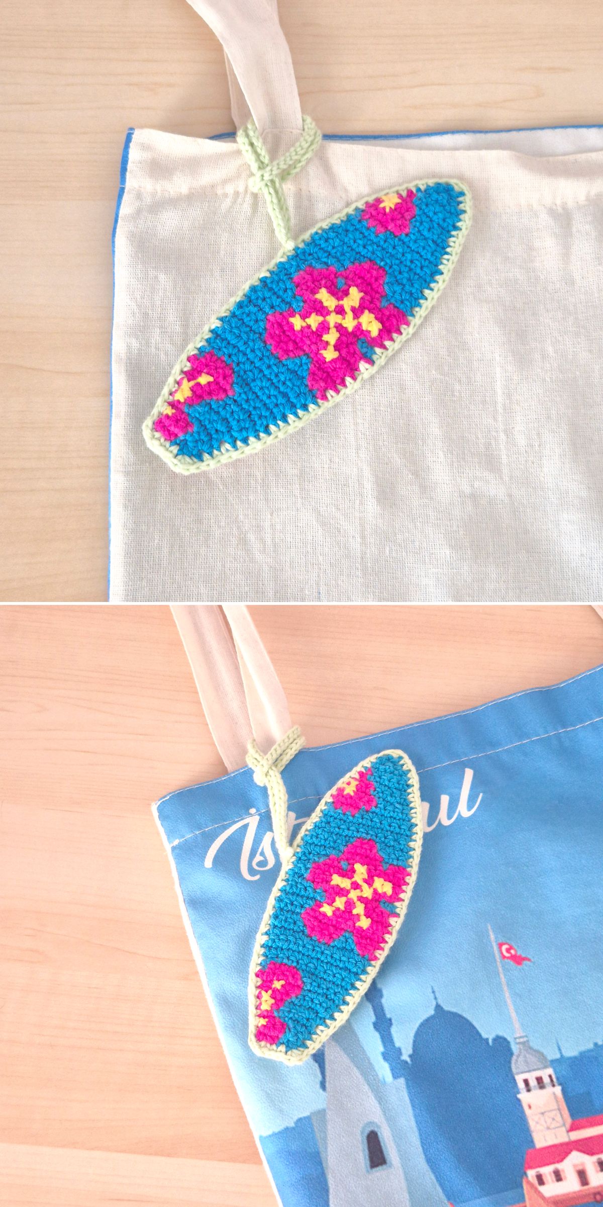 A crochet bag charm shaped like a surfboard, featuring a blue background with pink and yellow flower designs, hangs on a fabric tote bag.