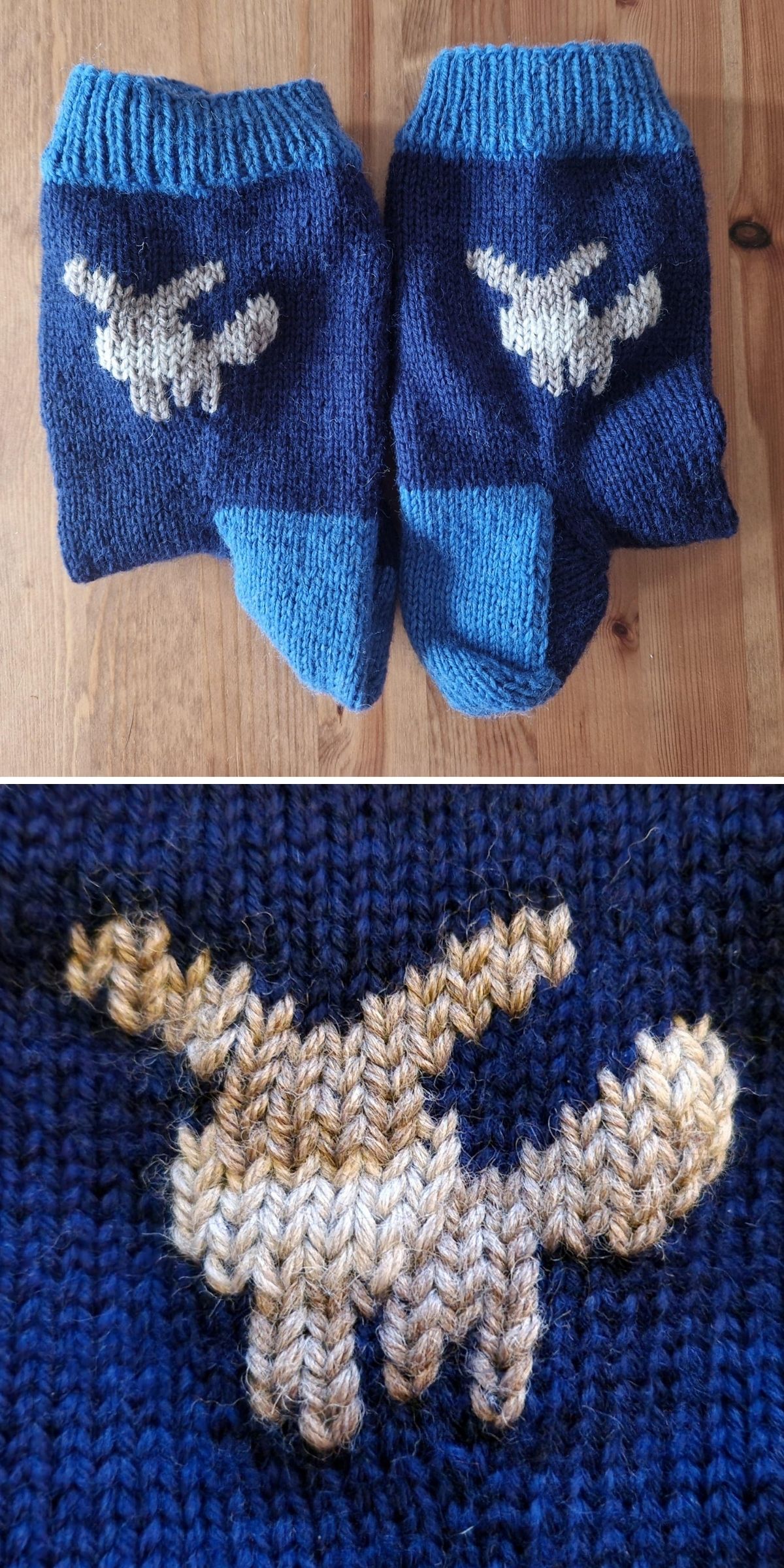 Two blue knitted socks with a lighter colored moose design on each are shown together in a close-up view on a wooden surface.
