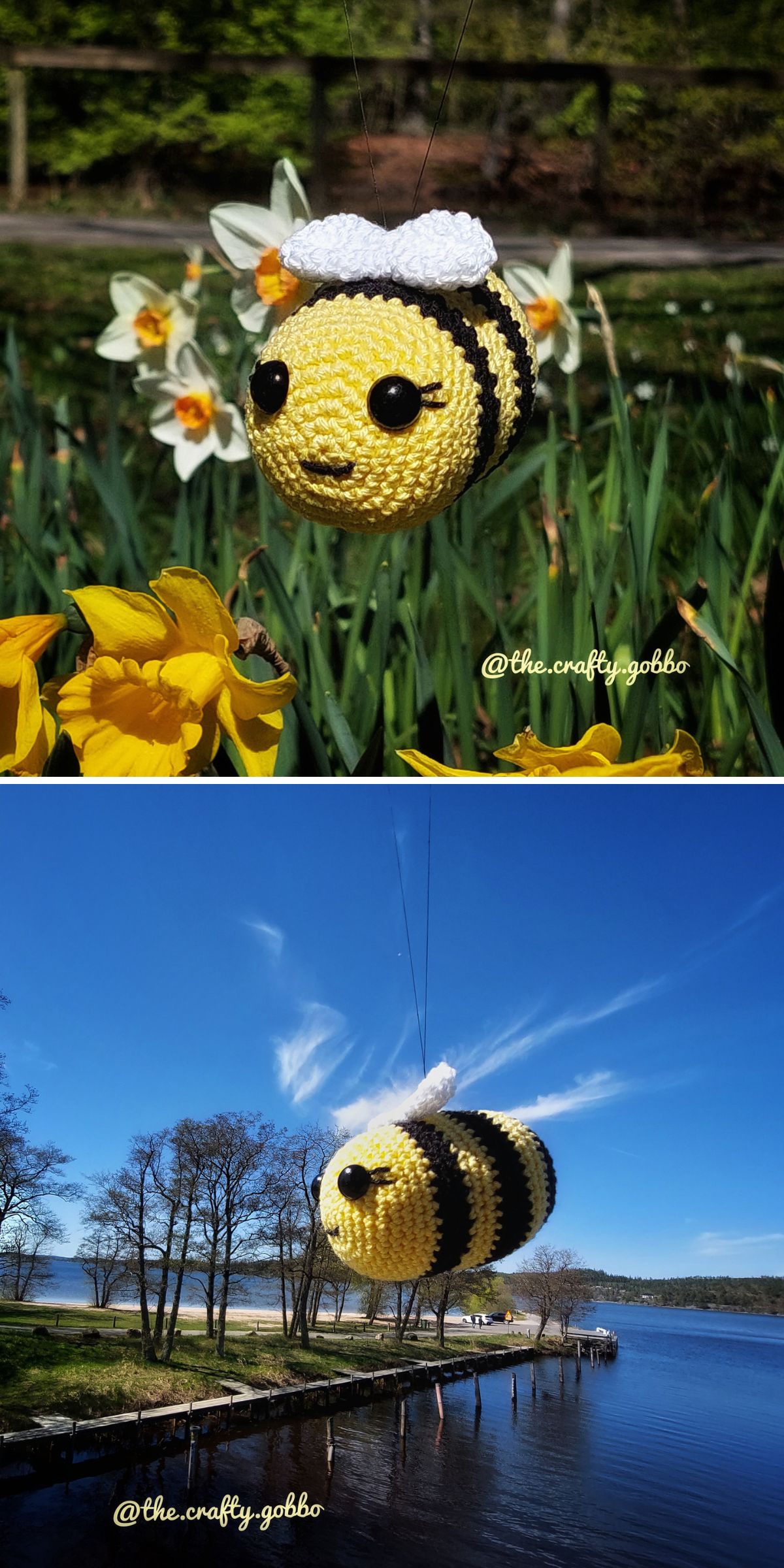 A crocheted bee with a white bow is suspended by a thread outdoors, shown among yellow flowers and above a lakeside landscape.