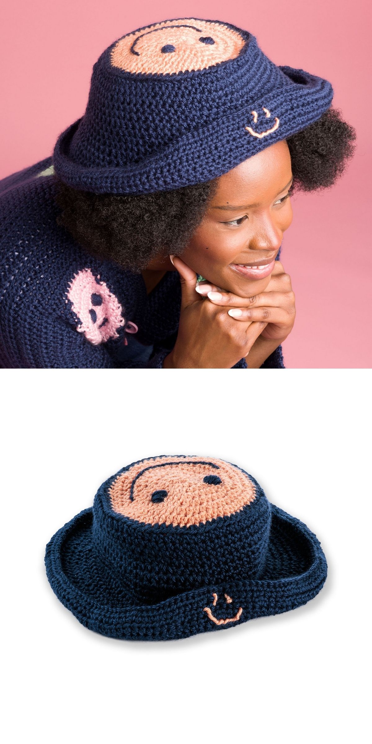 A person wears a navy blue funny crochet hat with a pink smiling face design on top and side, shown both on a model and alone against a white background.